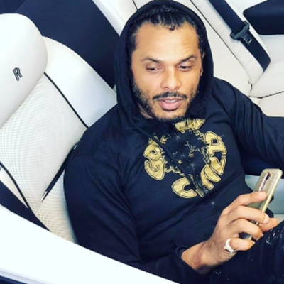 Back of a man at a concert. Hes wearing a beanie hat and a baggy denim jacket with studs. Photo with a purple hue